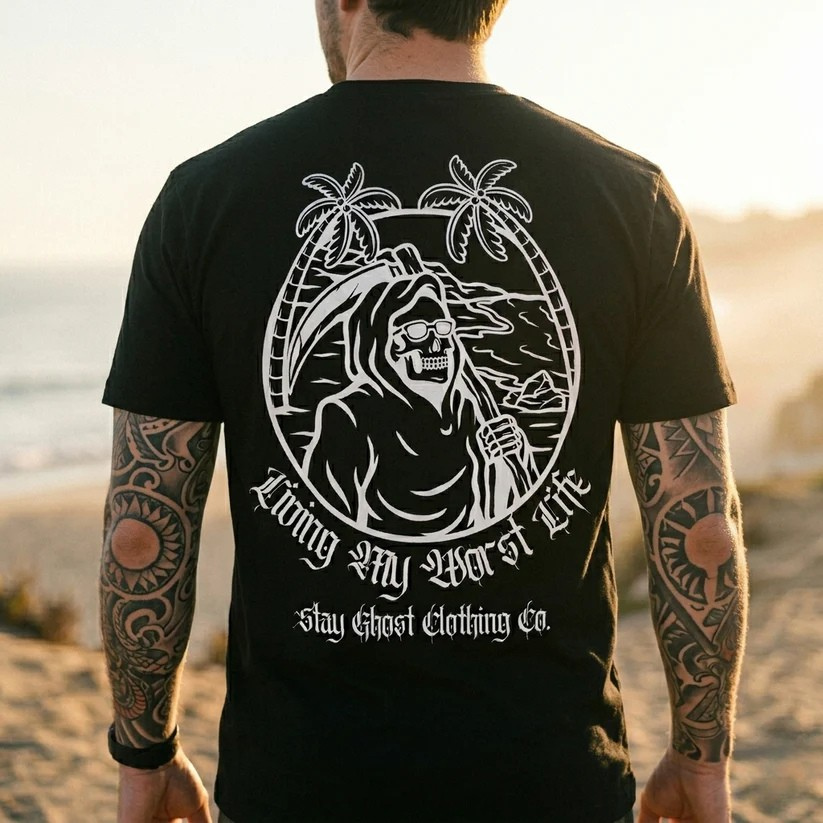 Person wearing a black t-shirt with a white graphic and text on the beach