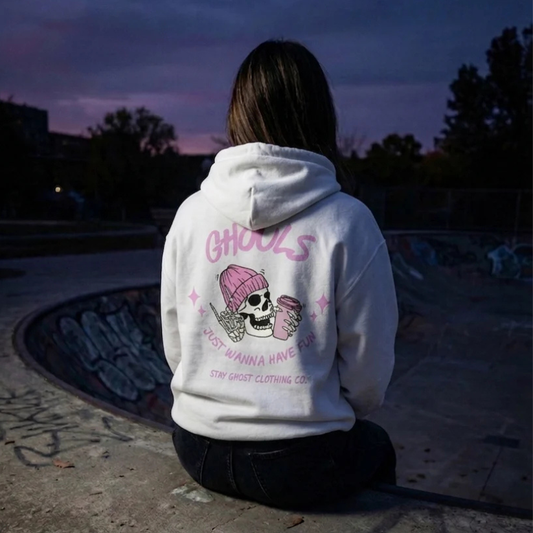 Person wearing a white hoodie with pink graphics and text, sitting in a dark outdoor setting.