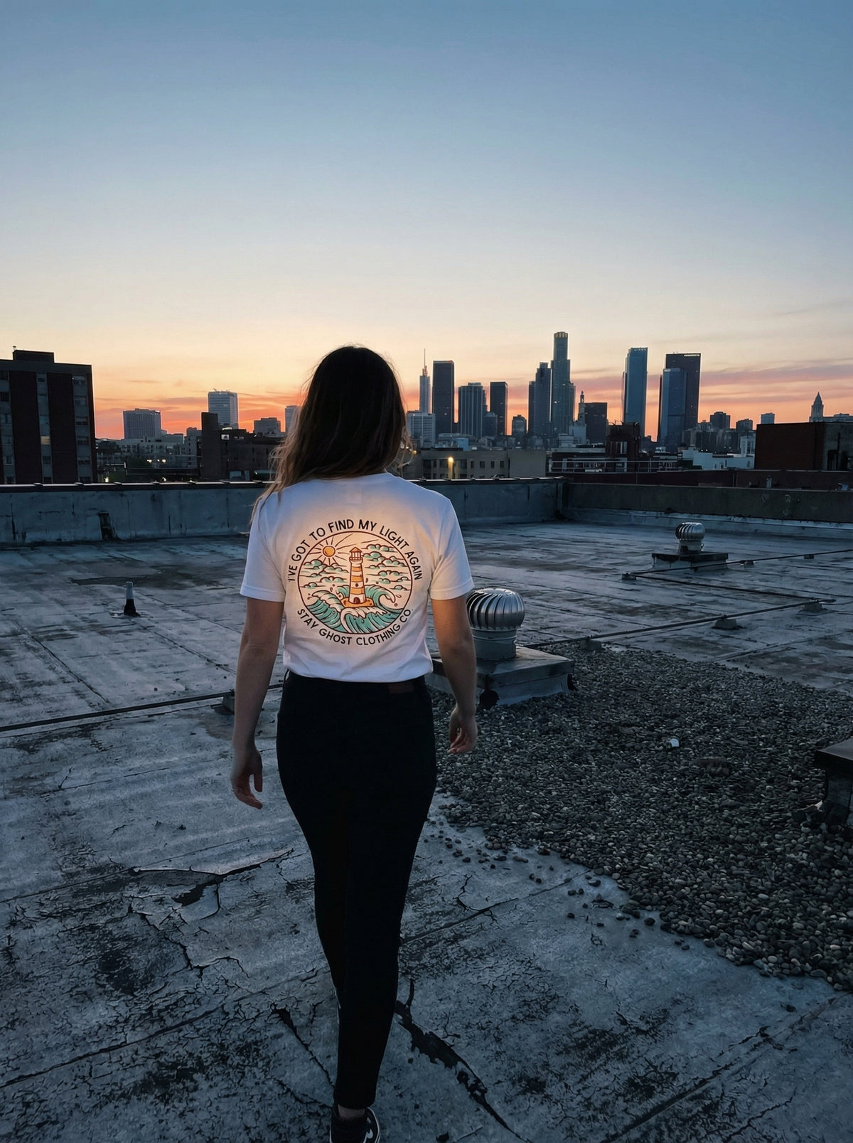 Person on a rooftop at sunset with a city skyline in the background
